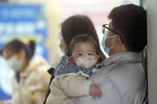 Un bebé con mascarilla espera con sus familiares en el departamento de pediatría de un hospital en Hangzhou, provincia oriental de Zhejiang, China, el 6 de enero de 2025. (AFP/Getty Images)