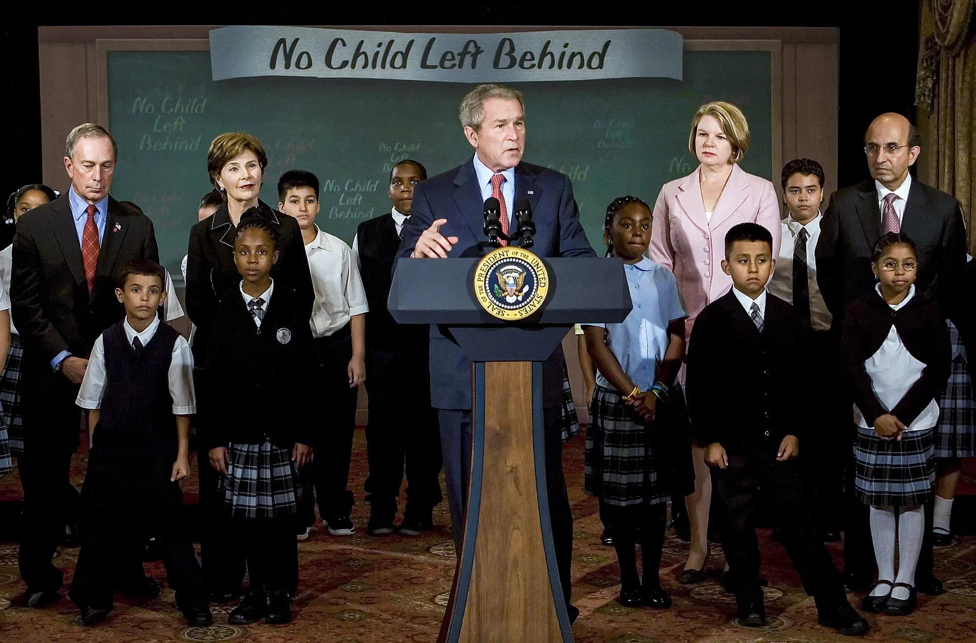 El presidente George W. Bush habla sobre la Ley Que Ningún Niño Se Quede Atrás con estudiantes de la Escuela Pública 76 de Nueva York, acompañado por (de izquierda a derecha) el alcalde de Nueva York, Michael Bloomberg, la primera dama, Laura Bush, la secretaria de Educación, Margaret Spellings, y el canciller de las Escuelas de la Ciudad de Nueva York, Joel Kline, en la ciudad de Nueva York el 26 de septiembre de 2007. (Jim Watson/AFP a través de Getty Images)