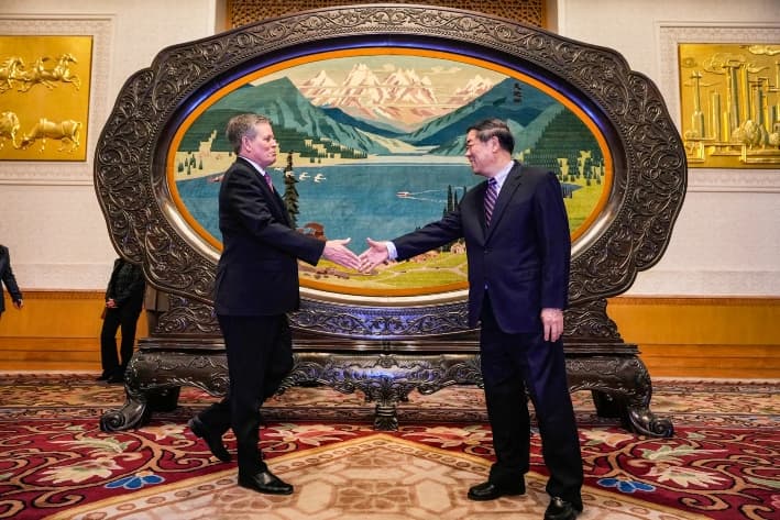 El viceprimer ministro chino He Lifeng (der.) muestra el camino al senador Steve Daines (R-Mo.) antes de una reunión celebrada en la Sala Xinjiang del Gran Salón del Pueblo de Beijing, el 22 de marzo de 2025. (NG HAN GUAN/Getty Images)