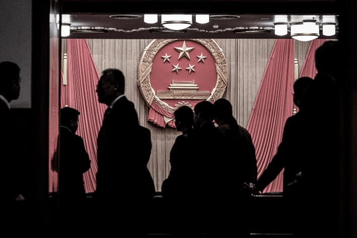 El emblema nacional se ve mientras los delegados y los agentes de seguridad se reúnen a la entrada del auditorio antes de la sesión de clausura de la Asamblea Popular Nacional en el Gran Salón del Pueblo en Beijing, el 11 de marzo de 2024. La Administración Trump está trabajando para frenar la influencia del Partido Comunista Chino sobre el Canal de Panamá y contrarrestar el proyecto de la Franja y la Ruta de Beijing. (Kevin Frayer/Getty Images)