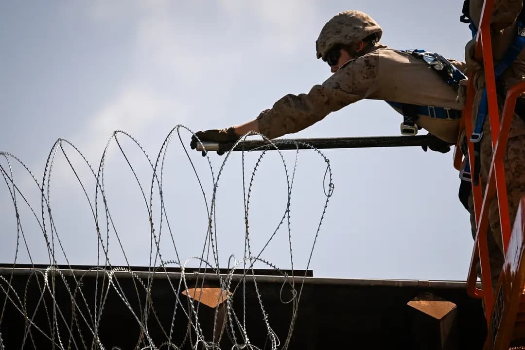 Personal militar estadounidense instala alambre de púas en lo alto del muro fronterizo entre Estados Unidos y México, cerca del puerto de entrada de San Ysidro, en San Diego, el 23 de abril de 2025. Desde que asumió el cargo en enero, el presidente Donald Trump ha lanzado una amplia campaña contra la inmigración ilegal, firmando órdenes ejecutivas para enviar tropas a la frontera, restablecer la política de "permanecer en México", poner fin a la "captura y liberación", reiniciar la construcción del muro fronterizo, designar a los cárteles como organizaciones terroristas extranjeras y poner fin a la ciudadanía por nacimiento. (Patrick T. Fallon/AFP a través de Getty Images)