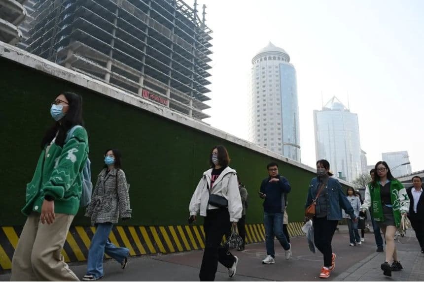 Varias personas pasan por delante de edificios en el distrito central de negocios de Beijing mientras se dirigen al trabajo el 11 de abril de 2025. (Greg Baker/AFP vía Getty Images)