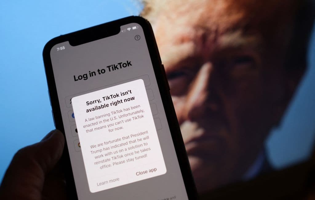 Esta foto ilustrativa tomada en Los Ángeles el 18 de enero de 2025 muestra la aplicación TikTok en la pantalla de un teléfono inteligente frente a una foto del presidente electo de EE. UU. Donald Trump. (CHRIS DELMAS/AFP vía Getty Images)
