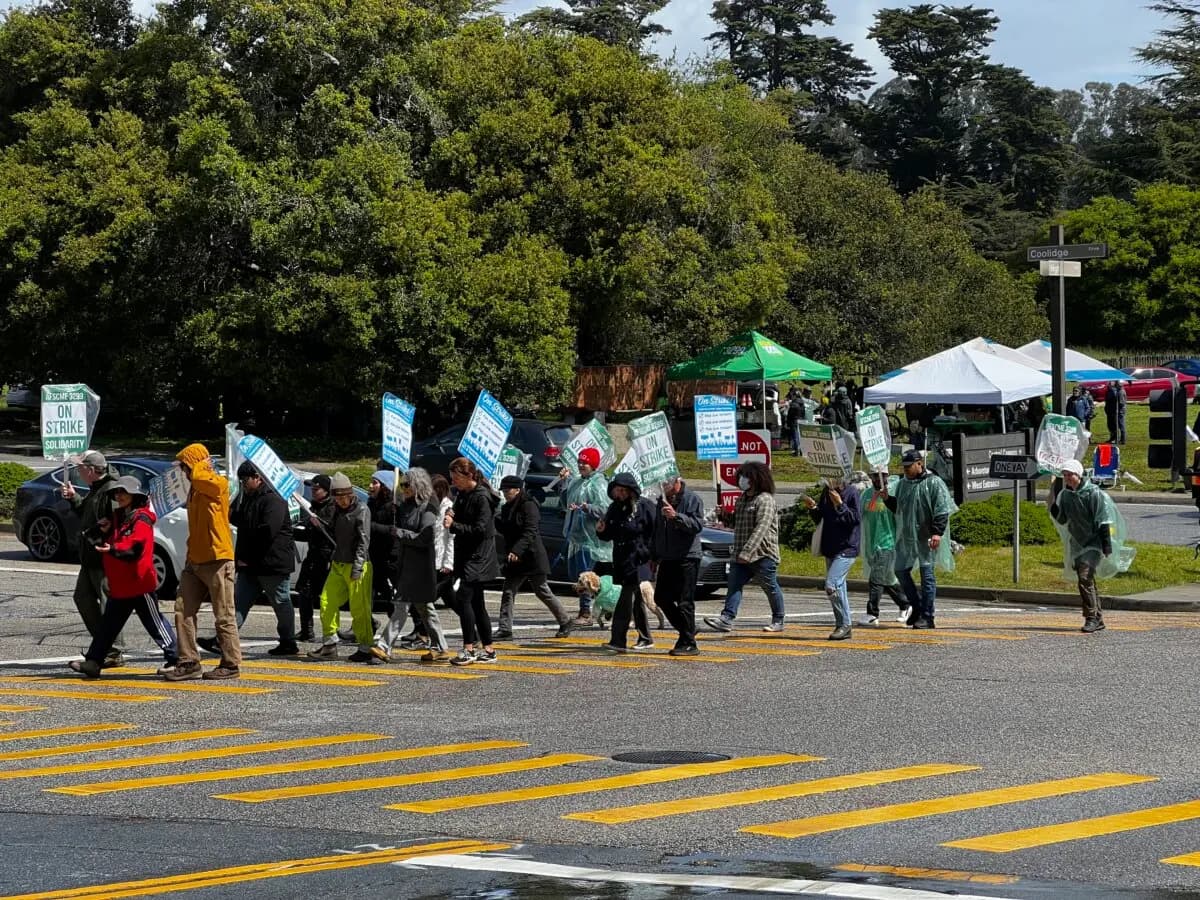 Trabajadores del sindicato cruzan la calle durante una huelga frente a la entrada de la UC Santa Cruz el 1 de abril de 2025. (Conner Lee/The Epoch Times)