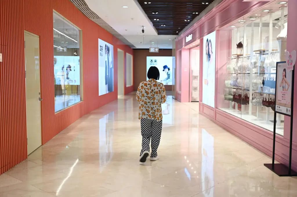 Una mujer pasa por delante de las tiendas de un centro comercial de Beijín el 18 de julio de 2023. (Greg Baker/AFP a través de Getty Images).