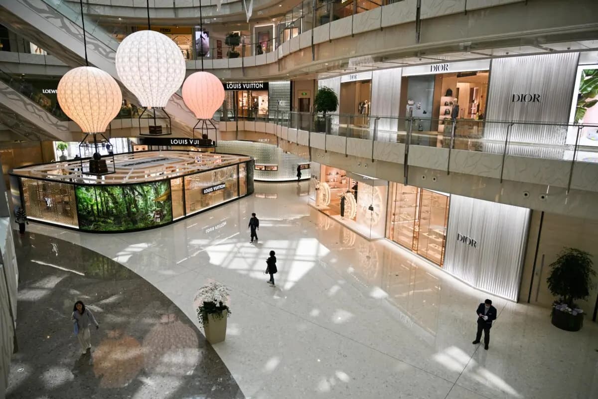 La gente pasa junto a las tiendas de marcas de lujo en un centro comercial del distrito financiero de Shanghái (China), el 14 de abril de 2025. (Hector Retamal/AFP a través de Getty Images)