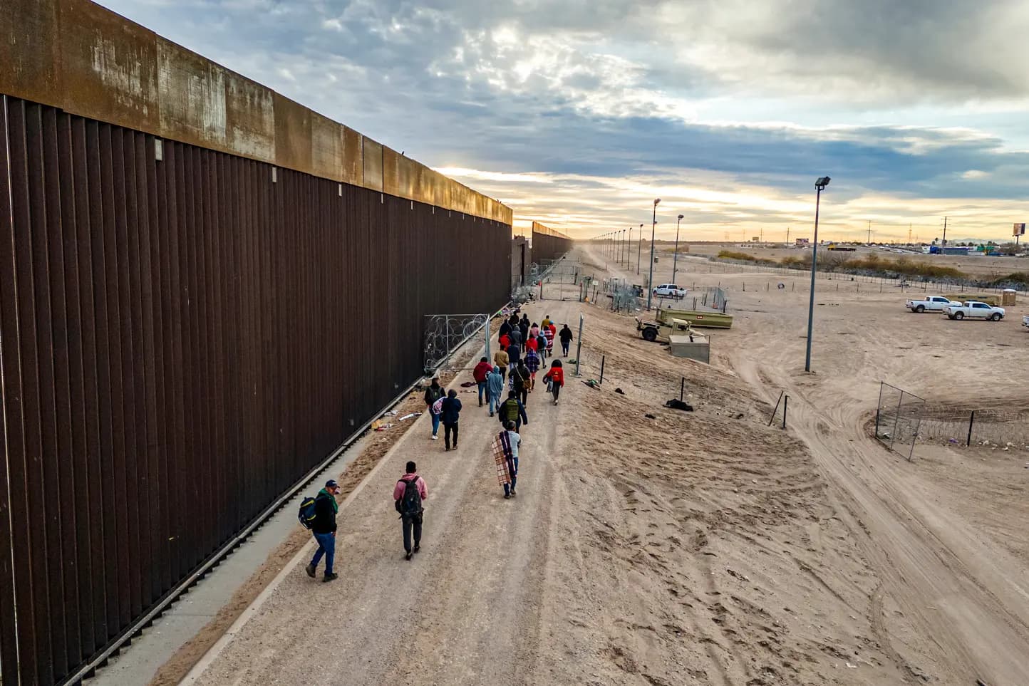 Inmigrantes ilegales caminan a lo largo del muro fronterizo entre Estados Unidos y México tras cruzar el río Grande hacia El Paso, Texas, el 1 de febrero de 2024. El capitán Troy Wilson, miembro de los Texas Rangers, declaró en una audiencia del Senado en mayo que las incursiones de drones a lo largo de la frontera entre Texas y México son un problema creciente. (John Moore/Getty Images).
