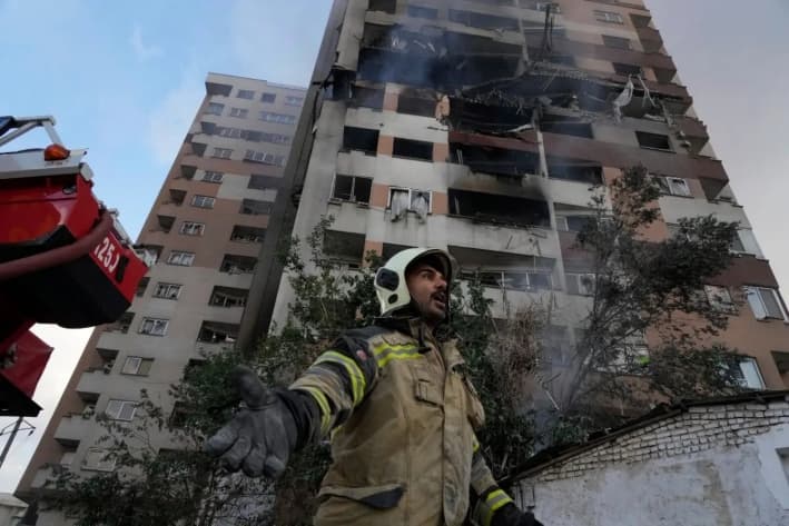 Un bombero llama a sus colegas en la escena de una explosión en un complejo residencial en el norte de Teherán, Irán, el 13 de junio de 2025. (Foto AP/Vahid Salemi)