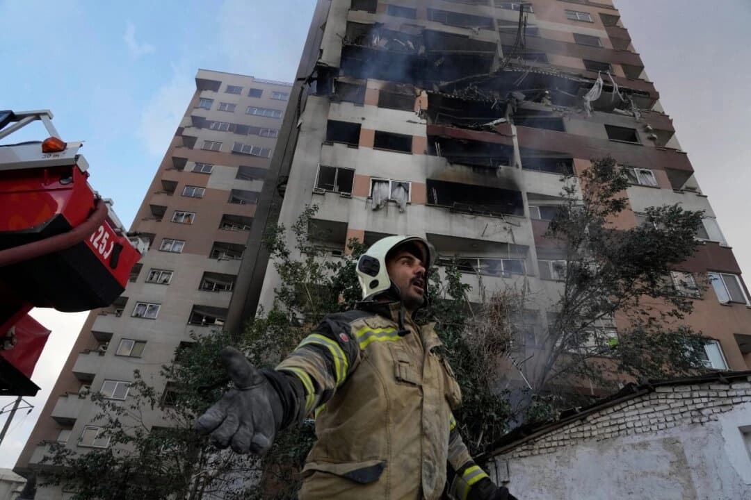 Un bombero llama a sus compañeros en el lugar de una explosión en un complejo residencial en el norte de Teherán el 13 de junio de 2025. (Vahid Salemi/AP Photo)