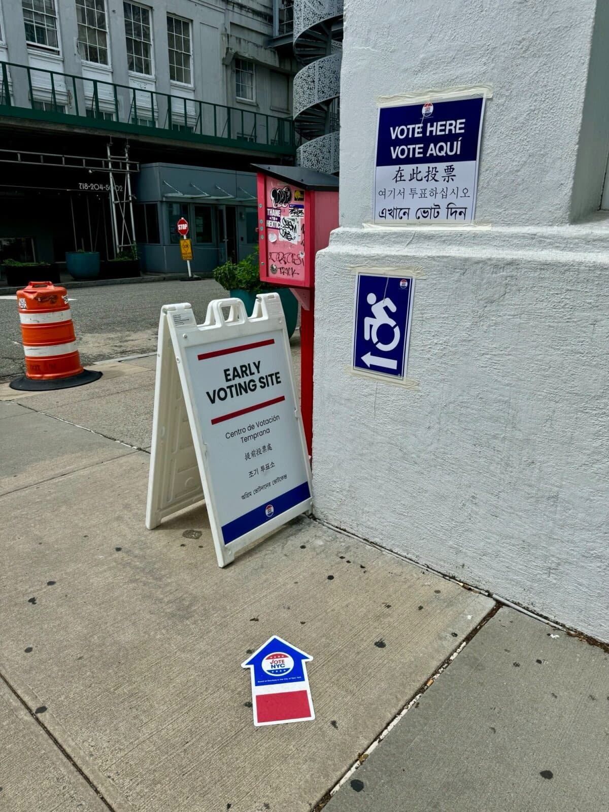 Se muestran carteles en varios idiomas fuera de un colegio electoral en Astoria, Queens, Nueva York, durante las primarias. (Arjun Singh/The Epoch Times).