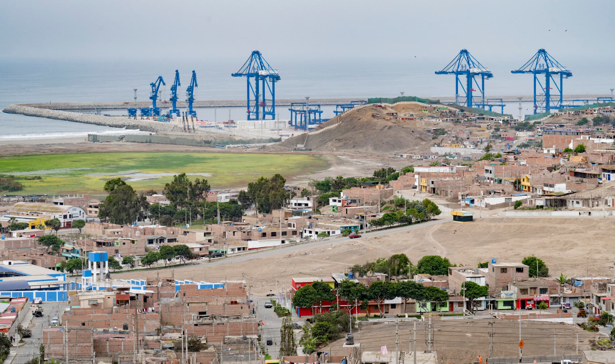 <em>Vista de las grúas del «megapuerto» de Chancay detrás de los barrios de la localidad de Chancay, a 78 kilómetros al norte de la capital peruana, Lima, el 29 de octubre de 2024. (CRIS BOURONCLE/AFP a través de Getty Images)</em>