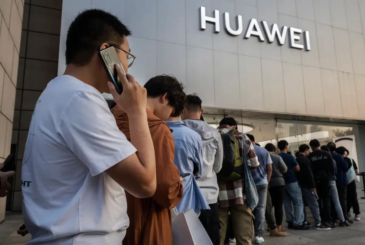 Un hombre habla por un teléfono móvil Huawei mientras él y otras personas hacen cola para comprar o reservar un nuevo smartphone Mate 60 y otros productos fuera de una tienda insignia de Huawei después de que la empresa presentara nuevos productos el 25 de septiembre de 2023 en Beijing, China. (Kevin Frayer/Getty Images)