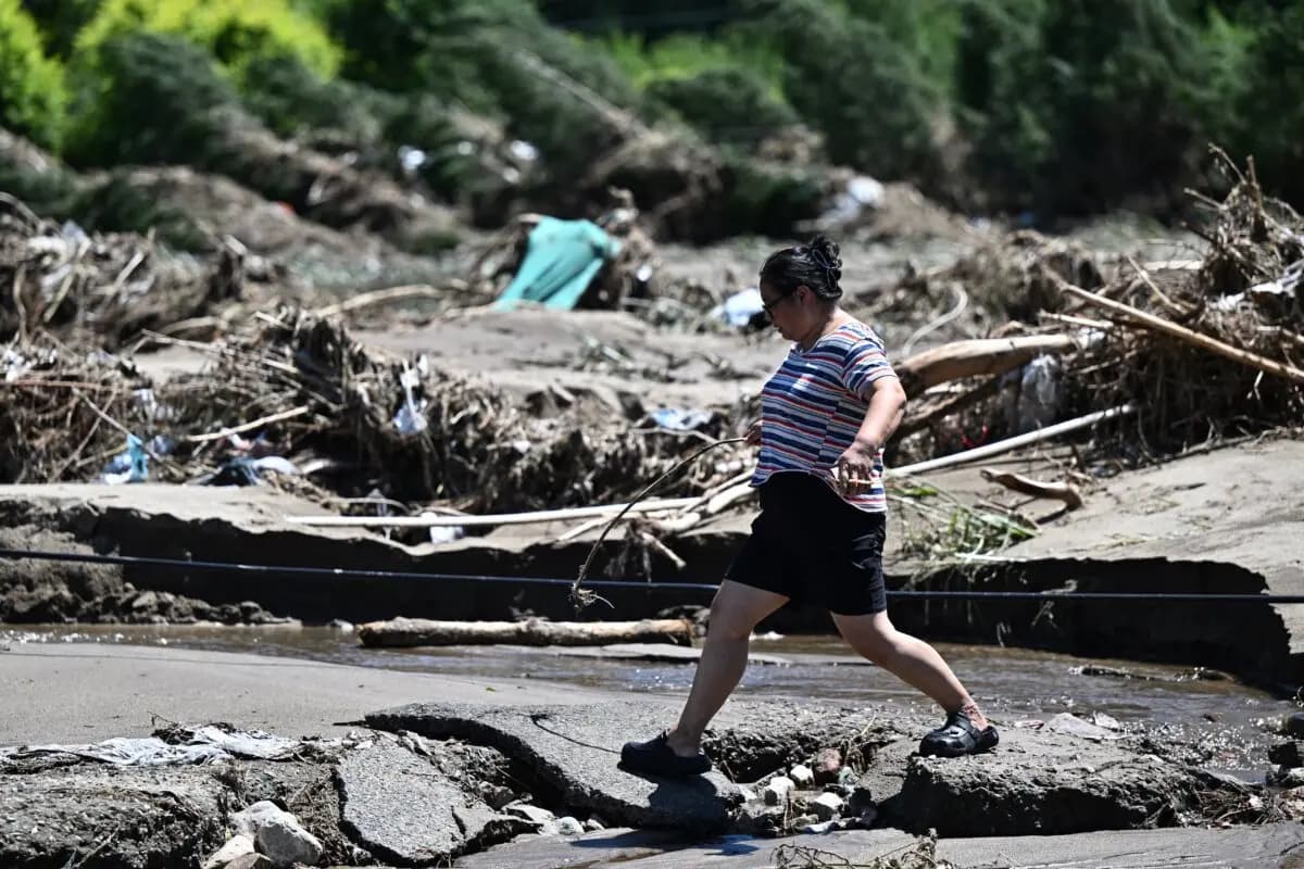 Una mujer camina junto a una zona inundada por las fuertes lluvias de los últimos días en el distrito de Huairou, a las afueras de Beijing, el 30 de julio de 2025. (Pedro Pardo/AFP vía Getty Images)