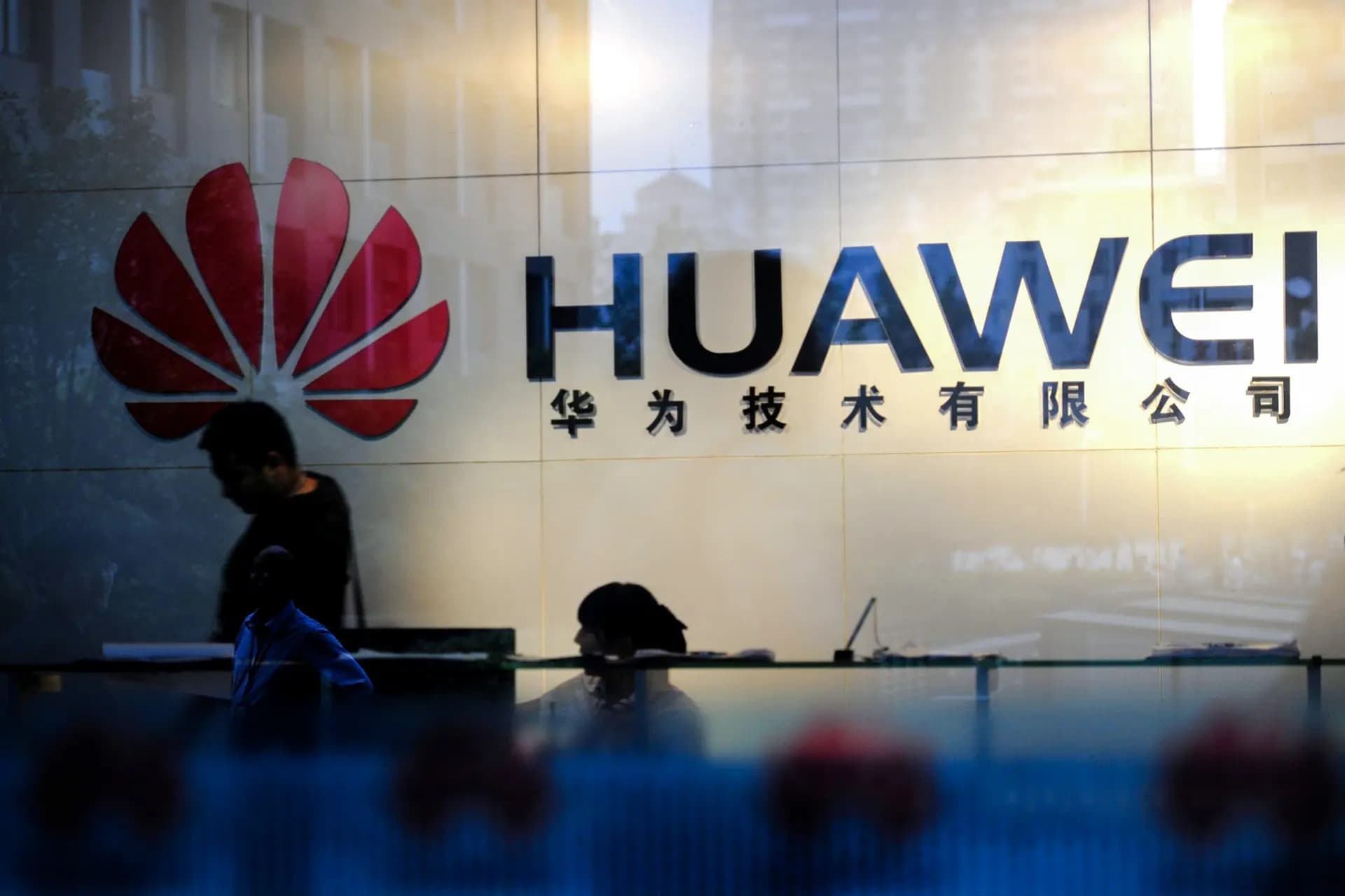 Personal y visitantes pasan por el vestíbulo de la oficina de Huawei en Wuhan, provincia de Hubei, China, el 8 de octubre de 2012. A principios de la década de 2000, legisladores, funcionarios y expertos de todo el mundo expresaron su preocupación por la seguridad nacional de los servicios de telecomunicaciones chinos, incluido Huawei.( STR/AFP/GettyImages)