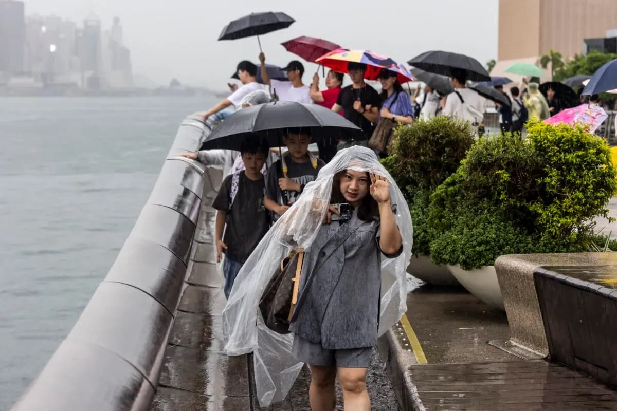 La gente utiliza paraguas para protegerse de la lluvia en Hong Kong el 14 de agosto de 2025, mientras el tifón Podul se debilita y se convierte en una tormenta tropical severa. (Isaac Lawrence /AFP a través de Getty Images)