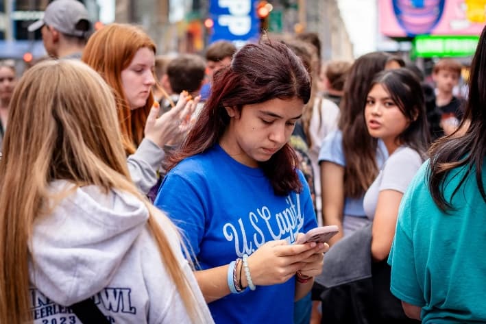 Una joven utiliza un teléfono móvil en la ciudad de Nueva York, el 10 de junio de 2024. Los expertos advierten que la avalancha de imágenes violentas en las redes sociales está distorsionando la actitud de las personas hacia la violencia. (Samira Bouaou/The Epoch Times)