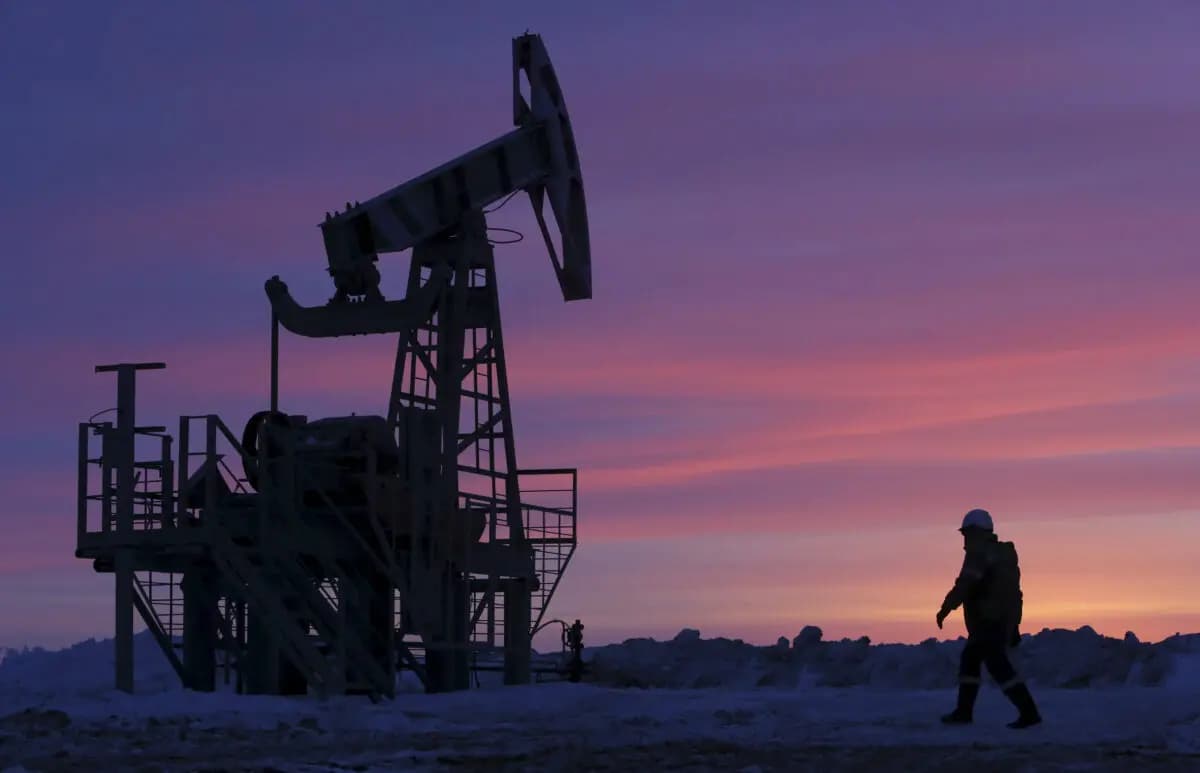 Un trabajador pasa junto a una bomba de extracción en un yacimiento petrolífero propiedad de la empresa Bashneft, cerca de la aldea de Nikolo-Berezovka, al noroeste de Ufa, Bashkortostán, Rusia, el 28 de enero de 2015. (Sergei Karpukhin/Reuters)