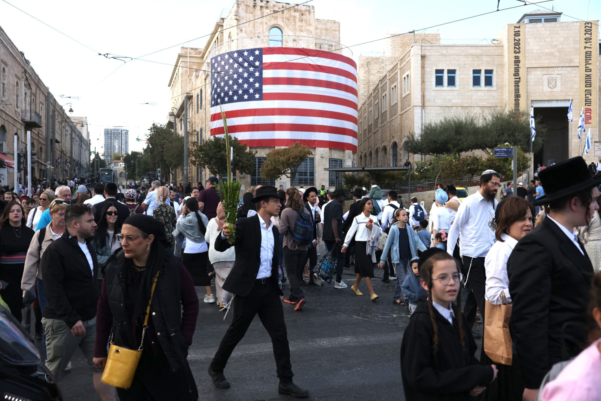 Israelíes pasan junto a una bandera estadounidense en el centro de Jerusalén antes de la llegada del presidente estadounidense Donald Trump, el 12 de octubre de 2025. (Ahmad Gharabli/AFP a través de Getty Images)