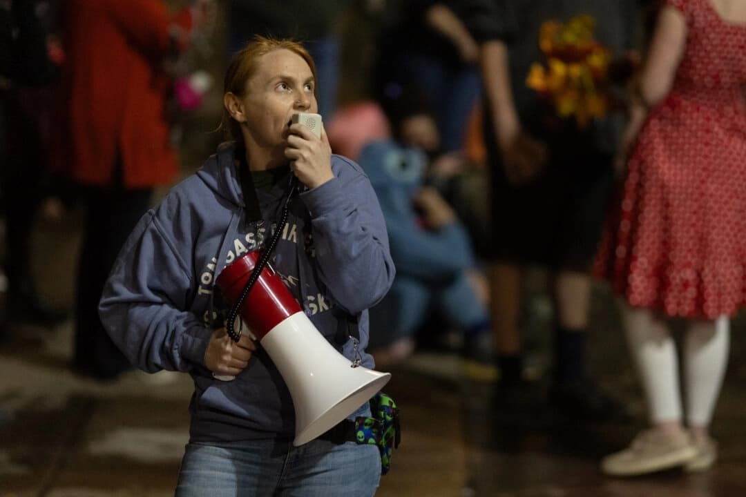 Una mujer habla por un megáfono frente a las oficinas del Servicio de Inmigración y Control de Aduanas en Portland, Oregón, el 4 de octubre de 2025. (John Fredricks/The Epoch Times)