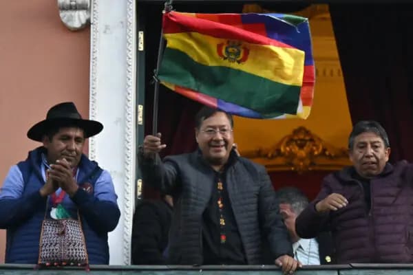 El presidente boliviano Luis Arce (C) ondea una bandera boliviana en el balcón del Palacio de gobierno en La Paz el 26 de junio de 2024. (Aizar Raldes/AFP).