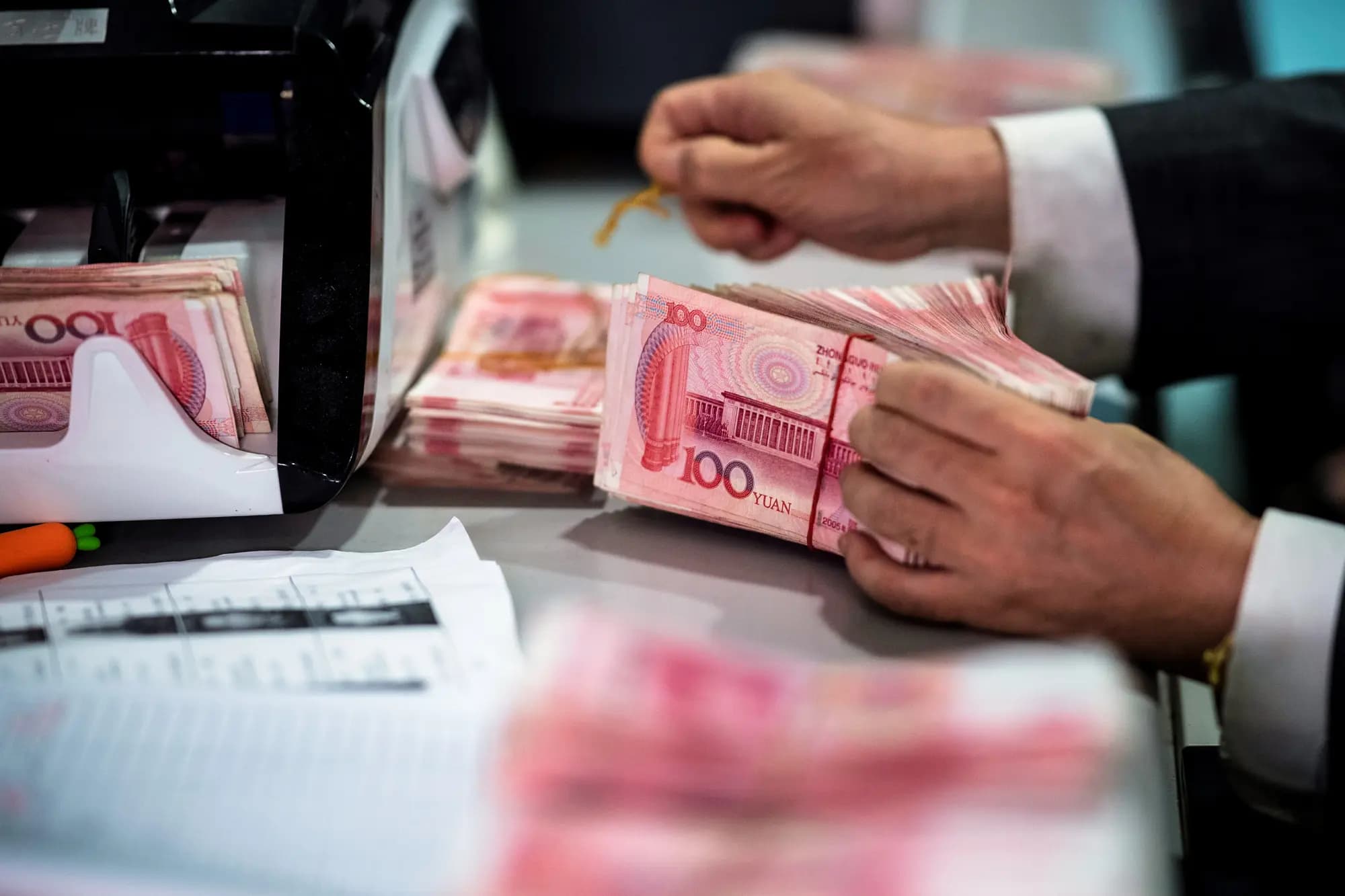 <em>Un empleado bancario cuenta billetes de 100 yuanes (14,60 dólares) en un banco de Shanghái el 8 de agosto de 2018. El régimen chino impuso un límite anual de cambio de divisas de 50,000 dólares en 2007 y, en 2016, anunció controles más estrictos sobre la revisión y aprobación de las conversiones de yuanes chinos a dólares estadounidenses. Johannes Eisele/AFP a través de Getty Images</em>