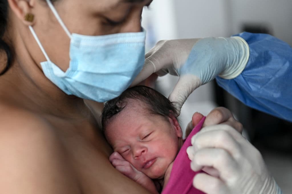 Una madre lleva a su bebé recién nacido mientras un médico la ayuda durante la pandemia del nuevo coronavirus COVID-19, en la sala de lactancia posparto del Hospital General de Medellín, en Medellín, Colombia, el 21 de mayo de 2020. (Foto de JOAQUIN SARMIENTO / AFP) (Foto de JOAQUIN SARMIENTO/AFP vía Getty Images)