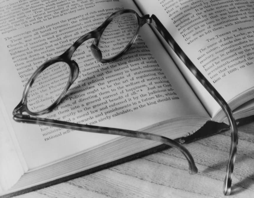 Un par de anteojos de carey sobre un libro abierto, EE. UU., circa 1970. (A. E. French/Archive Photos)