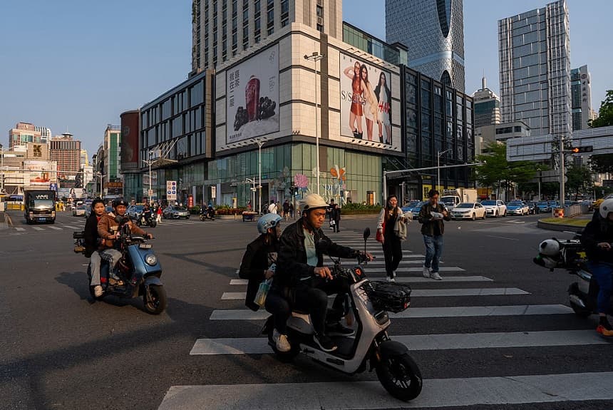Peatones y motociclistas cruzan un paso de peatones en un distrito comercial el 3 de abril de 2025 en Shenzhen, Guandong. (Getty Images/Getty Images)
