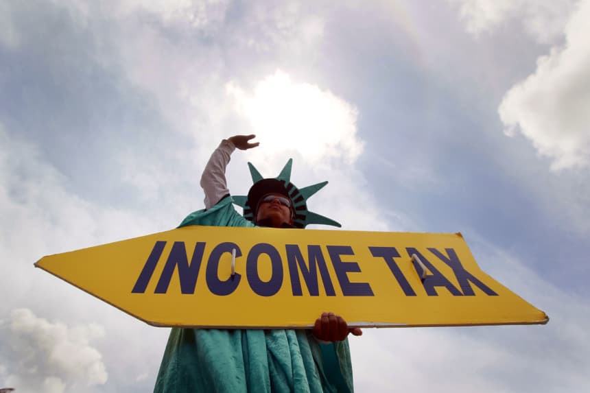 Felipe Castro sostiene un cartel que anuncia una oficina de preparación de impuestos para personas que aún necesitan ayuda para completar sus declaraciones antes de la fecha límite del Internal Revenue Service (IRS), el 14 de abril de 2010 en Miami, Florida. (Joe Raedle/Getty Images)