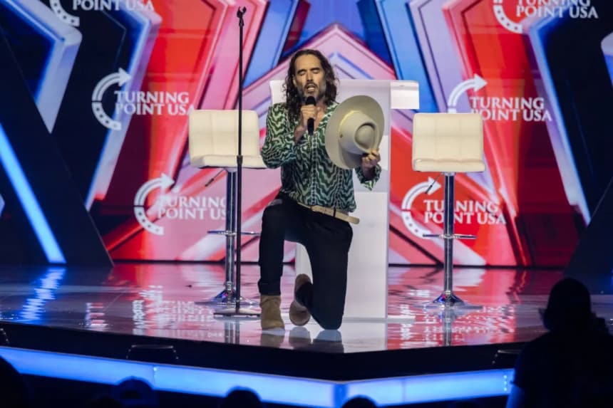 Russell Brand reza en el AmericaFest de Turning Point USA en Phoenix, el 18 de diciembre de 2025. (John Fredricks/The Epoch Times)
