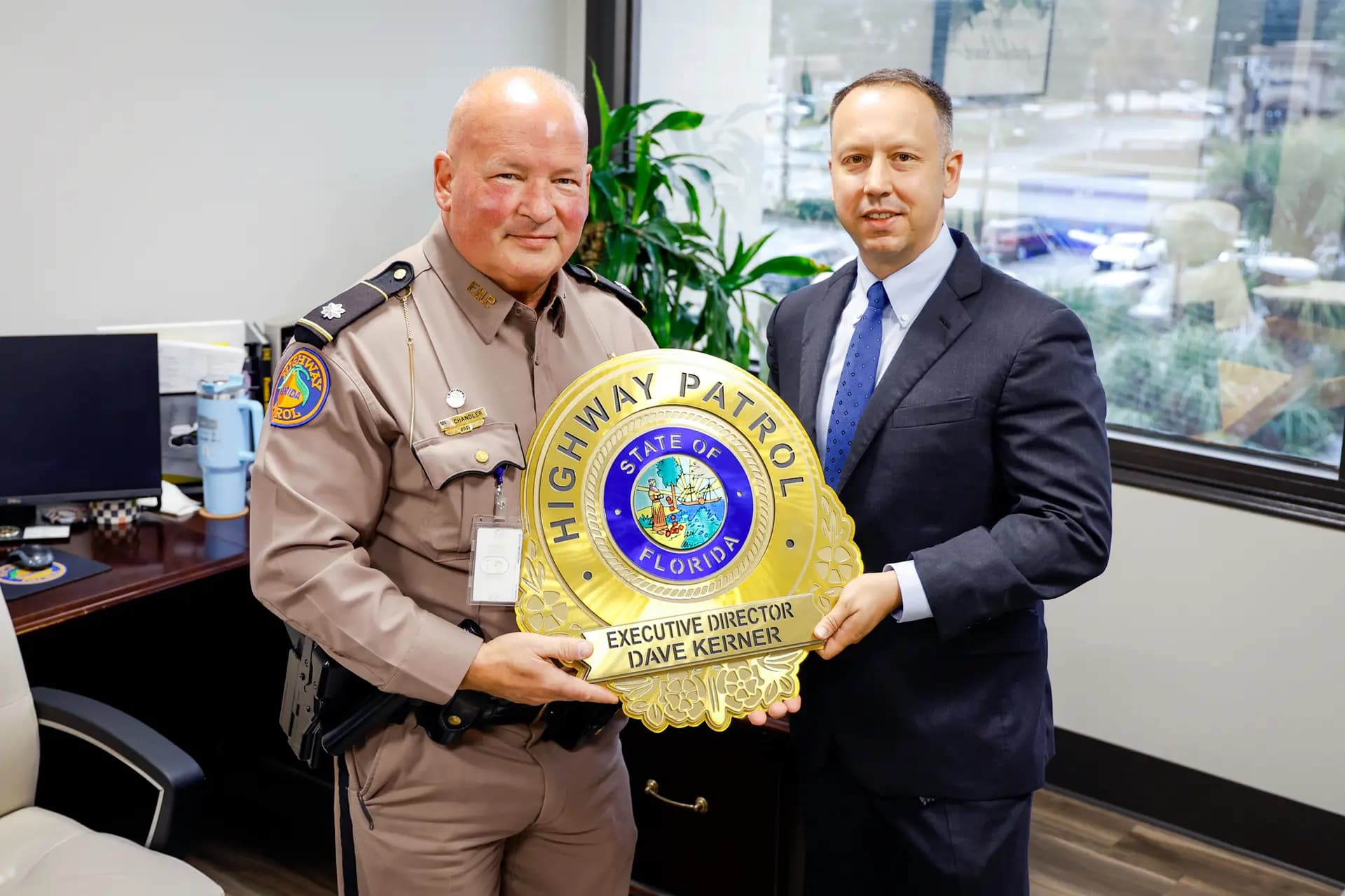 Dave Kerner (derecha) recibe una placa del teniente coronel Robert Chandler (izquierda), de la Patrulla de Carreteras de Florida, en Tallahassee, Florida, el 8 de diciembre de 2025. (Natasha Holt para The Epoch Times)