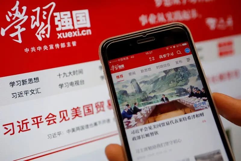 <em>La aplicación de propaganda comunista china "Xuexi Qiangguo", que literalmente se traduce como "Estudia para fortalecer China", en un teléfono móvil frente a su sitio web en un ordenador, en esta imagen ilustrativa tomada el 18 de febrero de 2019. (Ilustración/Tingshu Wang/Reuters)</em>