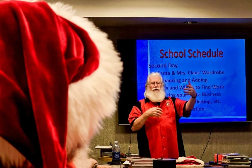Un alumno con un gorro rojo y blanco de Papá Noel escucha mientras Tim Conneghan (derecha) comenta las lecciones del día sobre cómo ser Papá Noel en Phoenix, el 3 de mayo de 2025. La escuela de Conneghan, la Universidad Internacional de Papá Noel, también conocida como School4Santas, ha formado a más de 5000 Papás Noel en los últimos 23 años. (Allan Stein/The Epoch Times)