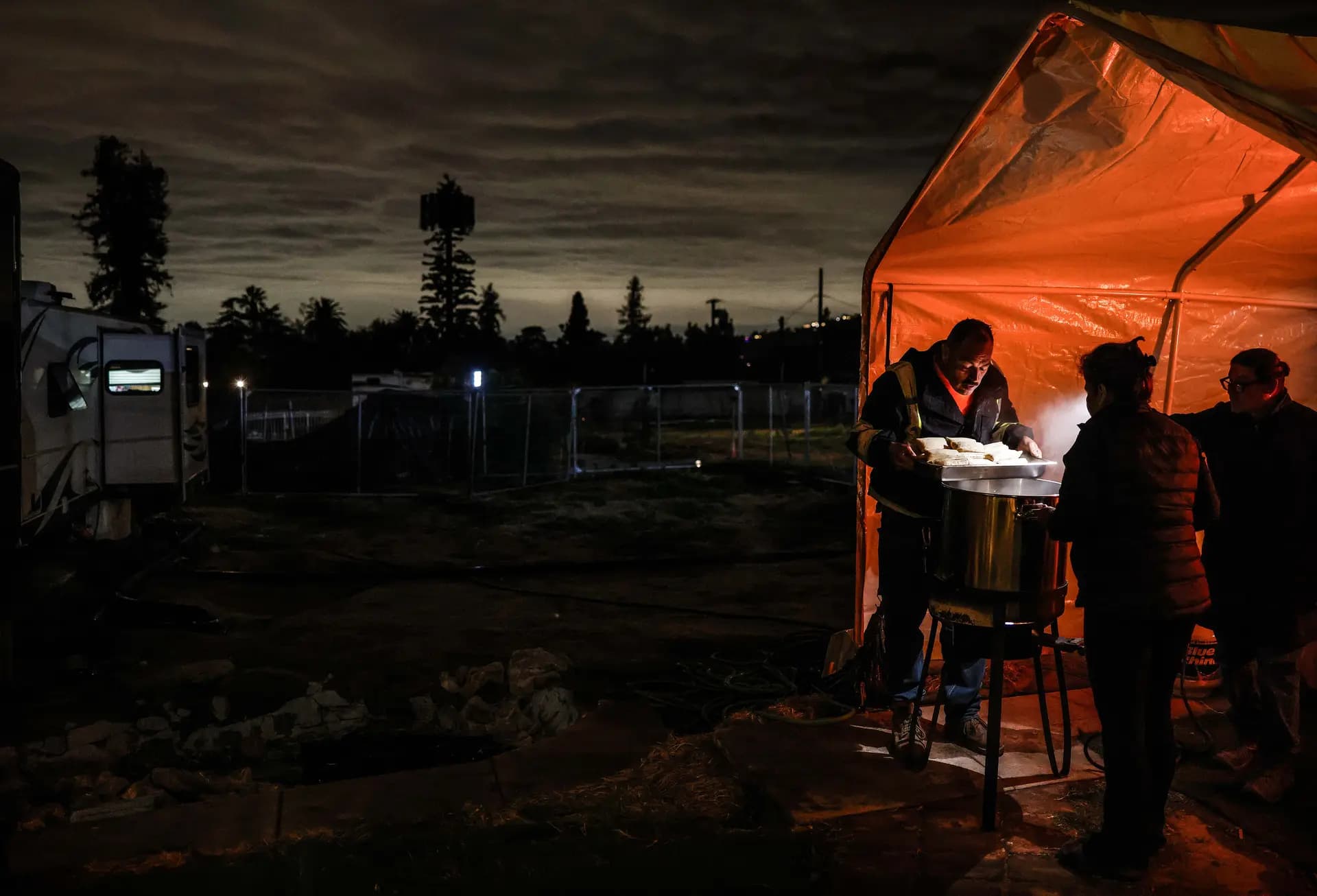 Leticia Serafín (2.ª der.) cocina tamales con su esposo Paul Fonseca (izq.) y su amigo Pedro Jiménez, antes de la tormenta de río atmosférico en Altadena, California, el 23 de diciembre de 2025. La pareja perdió su casa de 25 años en el incendio Eaton y reside en un remolque de viaje donado en su propiedad mientras hace planes para reconstruir. Ellos hacen tamales cada año para distribuirlos a familiares y amigos en la Nochebuena y mantuvieron la tradición este año. Mario Tama/Getty Images