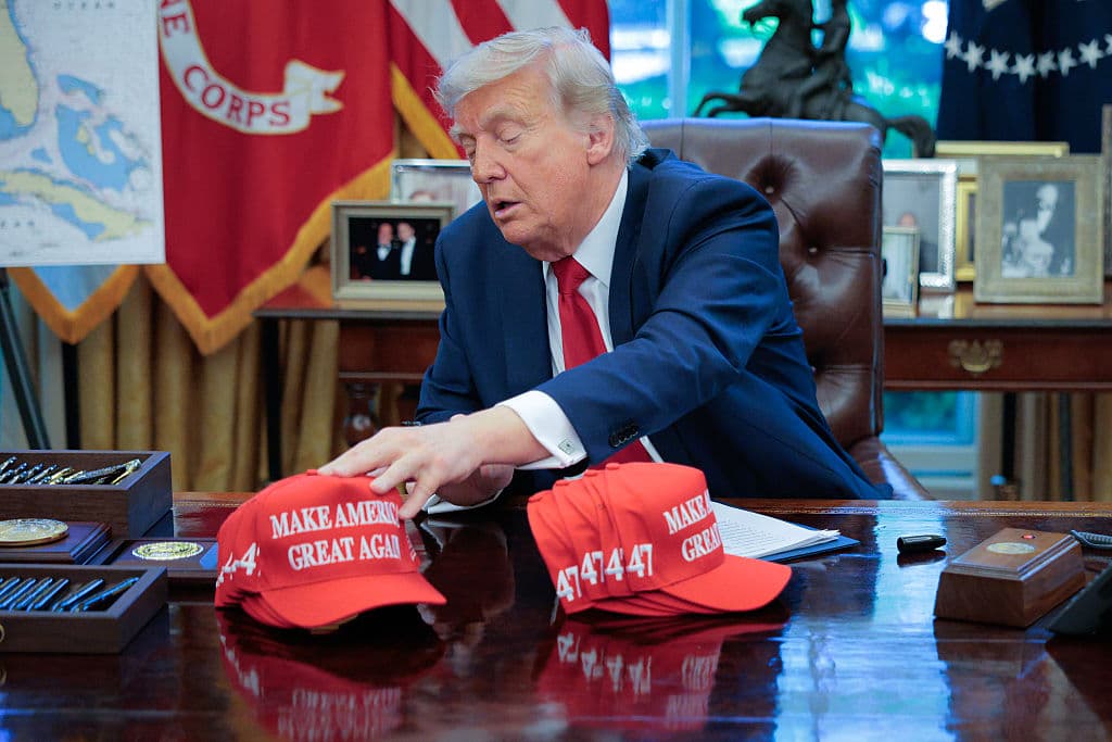El presidente estadounidense Donald Trump toma la gorra de "Make America Great Again" mientras se prepara para firmar órdenes ejecutivas en la Oficina Oval de la Casa Blanca el 23 de abril de 2025 en Washington, D.C. (Foto de Chip Somodevilla/Getty Images)