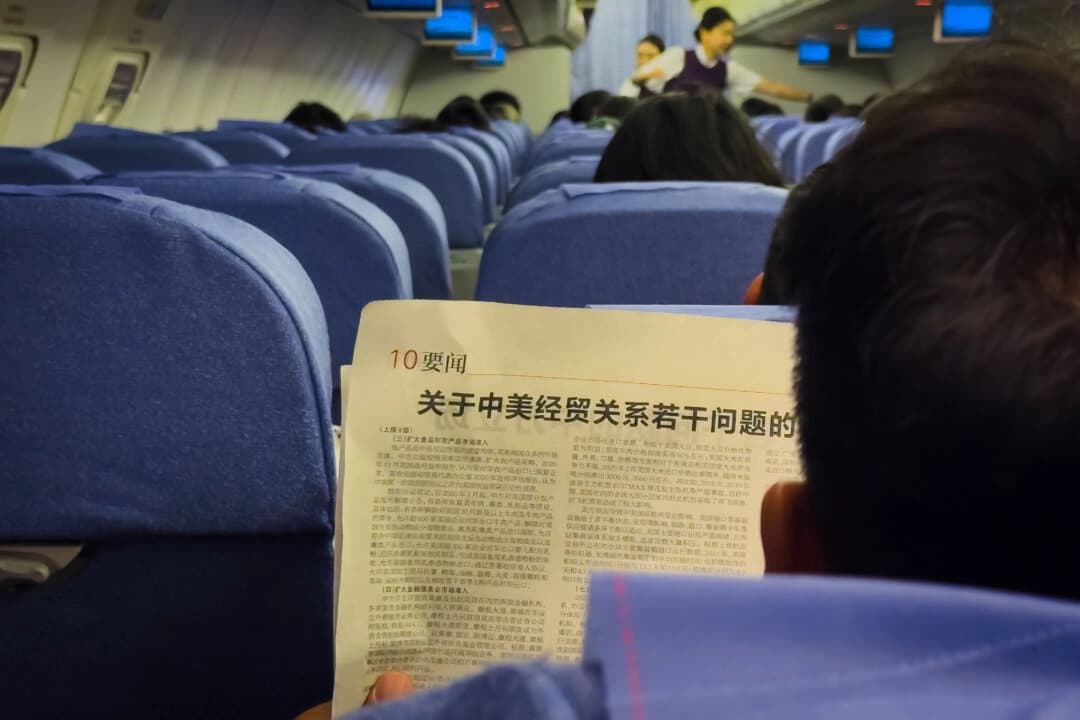 Pasajero de una aerolínea, viajando de Chongqing a Shenzhen, lee un artículo de periódico titulado "La posición de China sobre varios temas relacionados con las relaciones económicas y comerciales entre China y Estados Unidos", que es parte de un libro blanco publicado por la Oficina de Información del Consejo de Estado de China el 9 de abril de 2025. (Cheng Xin/Getty Images)