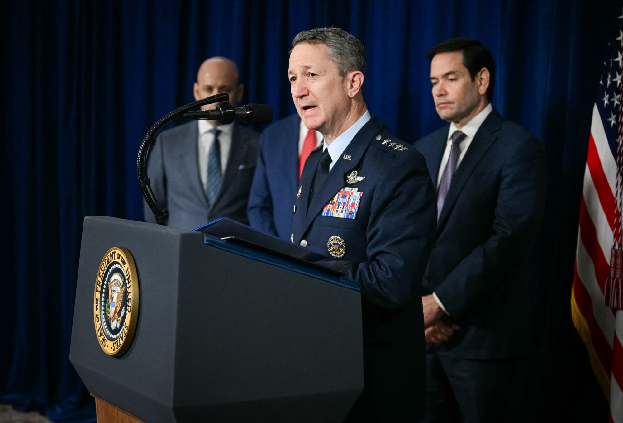 <em>El jefe del Estado Mayor Conjunto, general Dan Caine, habla a los reporteros sobre las acciones militares estadounidenses en Venezuela, mientras el secretario de Estado, Marco Rubio (der.) y el subjefe del Estado Mayor de la Casa Blanca, Stephen Miller (izq.) observan, durante la conferencia de prensa del presidente Trump en su residencia de Mar-a-Lago en Palm Beach, Florida, el 3 de enero de 2026. (Jim Watson/AFP vía Getty Images)</em>