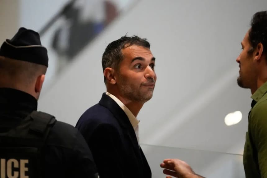 El acusado Aurelien Poirson-Atlan, en el centro, llega a la sala del tribunal mientras 10 personas son juzgadas por ciberacoso a Brigitte Macron tras difundir afirmaciones de que la esposa del presidente Emmanuel Macron era un hombre, en París, el 27 de octubre de 2025. (Michel Euler/AP Photo)