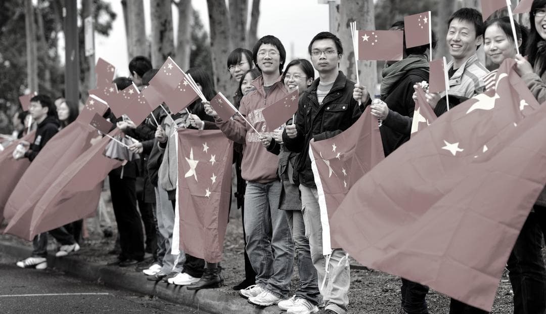 El personal consular chino ondea banderas nacionales frente a la Universidad RMIT mientras el líder chino Xi Jinping inaugura el primer Instituto Confucio de Medicina China de Australia en Melbourne, Australia, el 20 de junio de 2010. (William West/AFP vía Getty Images)