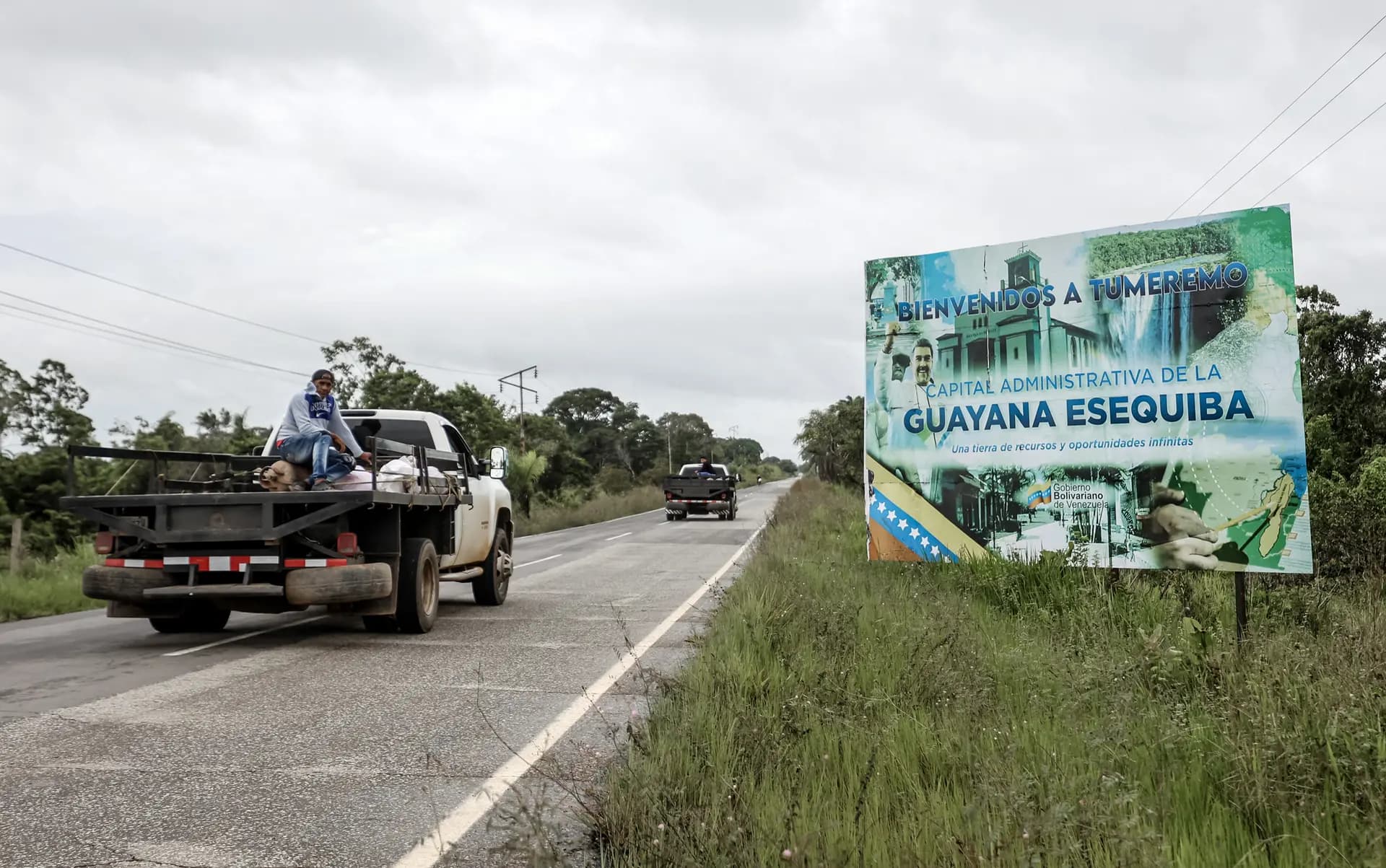 <em>Vehículos pasan junto a un letrero que indica la entrada a Tumeremo, la capital administrativa de la Guayana Esequiba, creada por Venezuela, el 26 de mayo de 2025. En abril de 2024 el entonces líder venezolano Nicolás Maduro firmó un proyecto de ley que estableció formalmente el estado venezolano de "Guayana Esequiba" e inició la ampliación de una base en la isla de Anakoko, en la confluencia de los ríos Cuyuni y Wenamu. (Pedro Mattey/AFP vía Getty Images)</em>