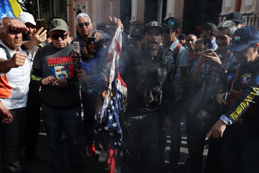 Miembros de la fuerza Colectivo y partidarios de Nicolás Maduro queman una bandera de Estados Unidos durante una concentración cerca del palacio de Miraflores tras escucharse explosiones y aviones volando a baja altura en la madrugada del 3 de enero de 2026 en Caracas, Venezuela. (Jesús Vargas/Getty Images)