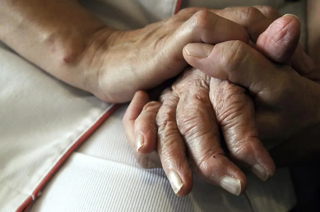 Una enfermera sostiene las manos de un paciente con Alzheimer en la residencia de ancianos Les Fontaines, en Lutterbach, Francia, el 21 de septiembre de 2009. (Sebastien Bozon/AFP a través de Getty Images).