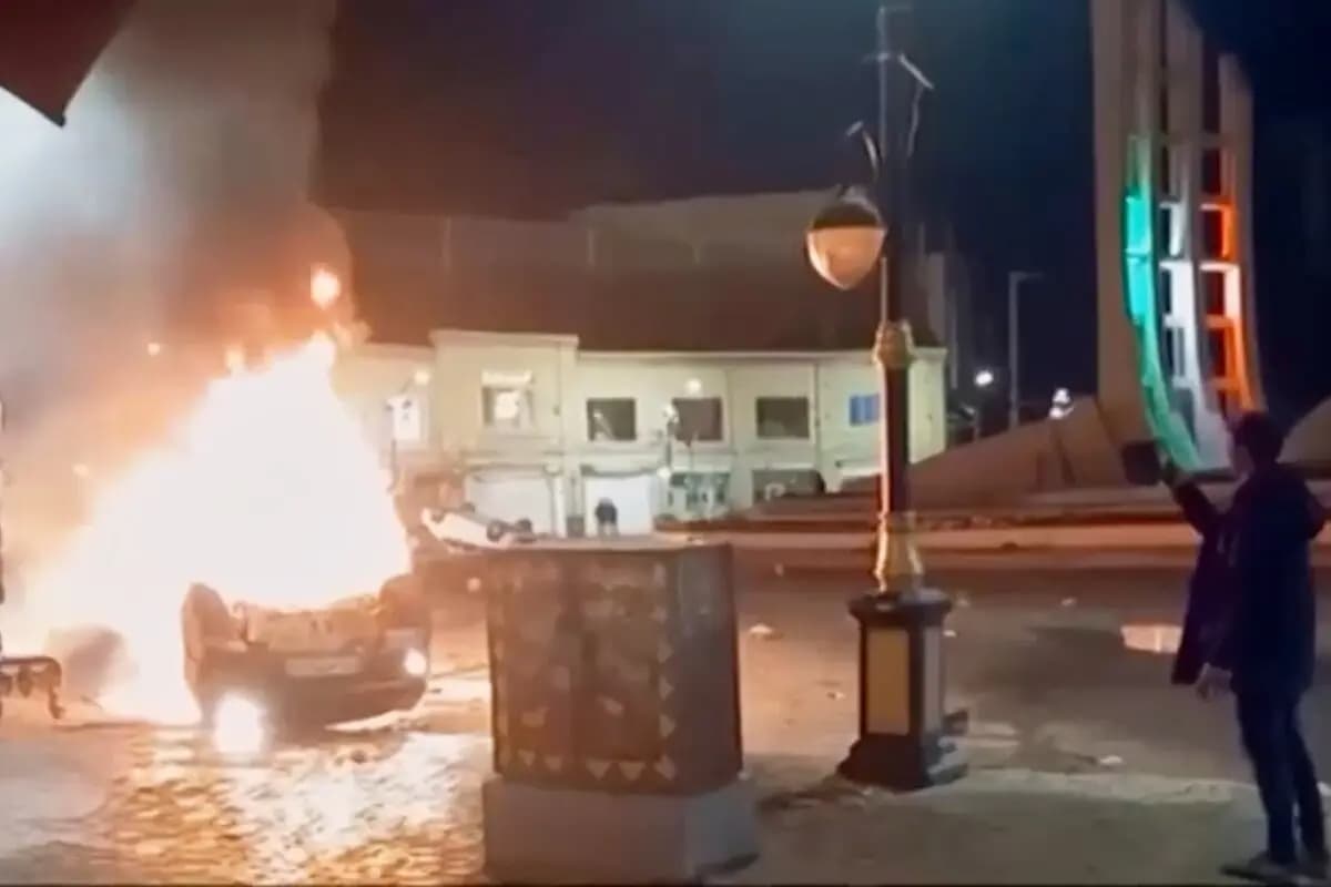 Una imagen capturada de la televisión estatal iraní muestra a un hombre observando vehículos en llamas durante las protestas nocturnas en Zanjan, Irán, el 9 de enero de 2026. (Televisión estatal iraní vía AP)