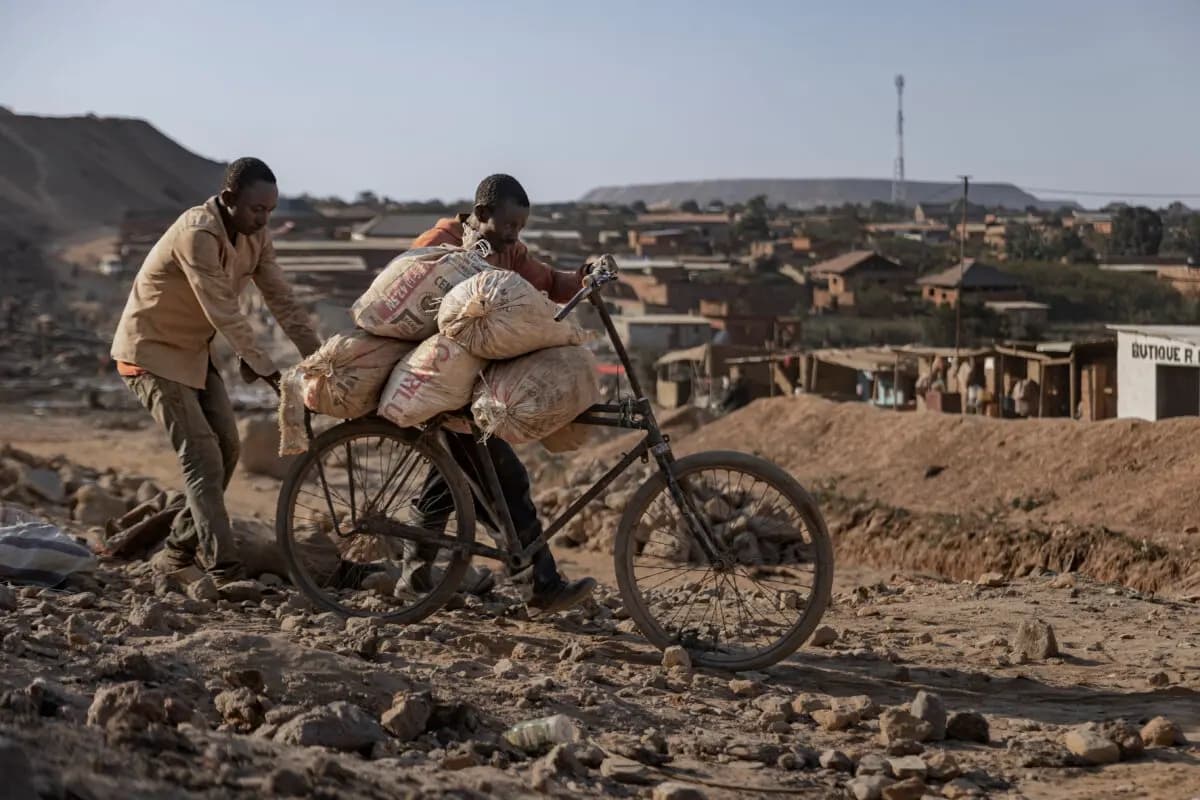 Un padre y su hijo empujan una bicicleta cargada con sacos de cobalto y cobre por un camino de tierra cerca de una mina artesanal en Kolwezi, República Democrática del Congo, el 25 de mayo de 2025. (Michel Lunanga/Getty Images)
