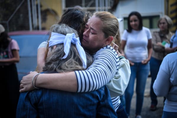 <em>Familiares de detenidos se abrazan tras rezar frente a un centro de detención en Boleita mientras esperan la liberación de presos políticos el 12 de enero de 2026 en Caracas, Venezuela. (Carlos Becerra/Getty Images)</em>