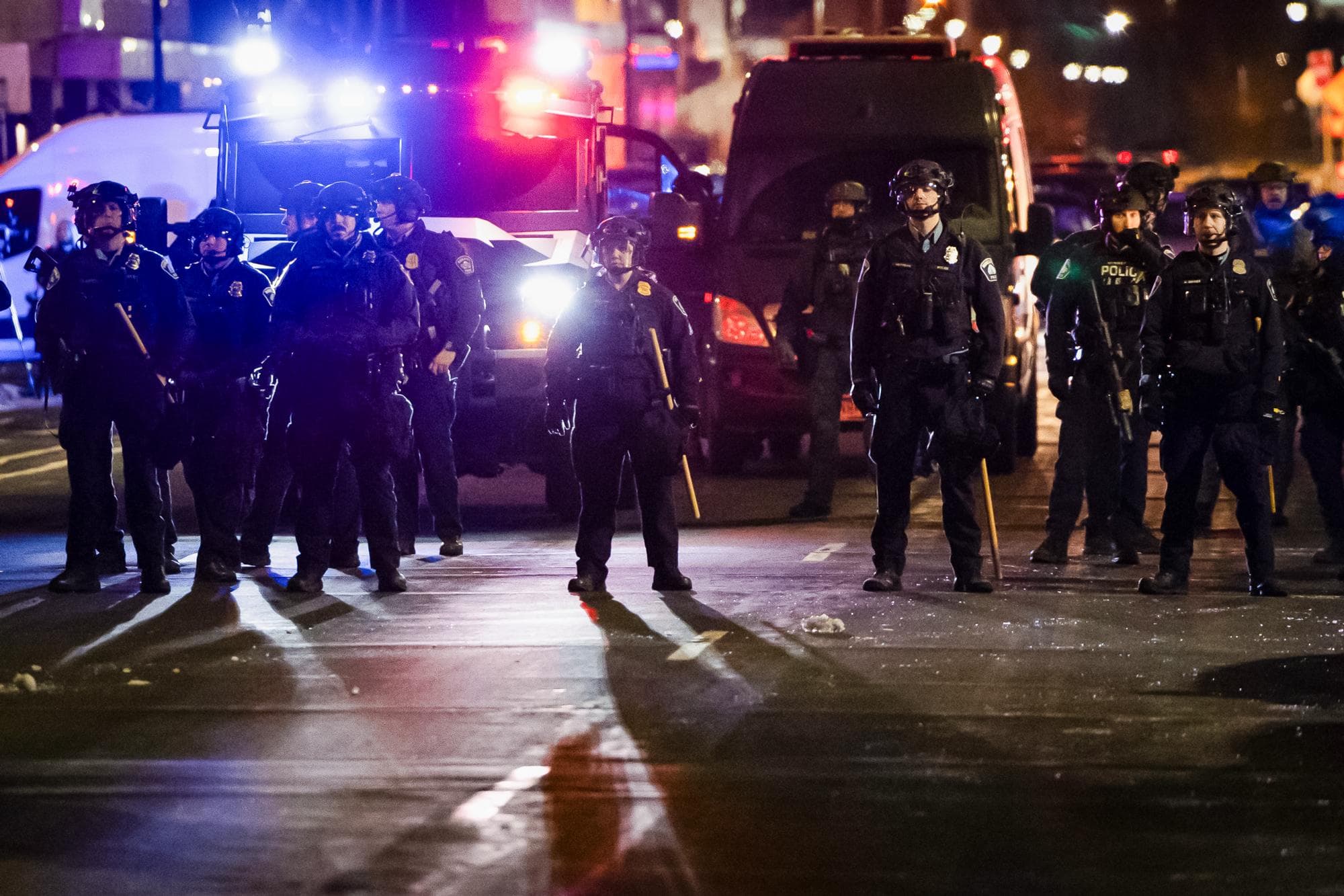 Arriba) Manifestantes protestan contra las operaciones federales de inmigración frente a oficiales de policía en Minneapolis el 9 de enero de 2026. (Abajo) Oficiales de policía se mantienen en formación durante una protesta contra las operaciones del ICE en Minneapolis el 9 de enero de 2026. (John Fredricks/The Epoch Times).
