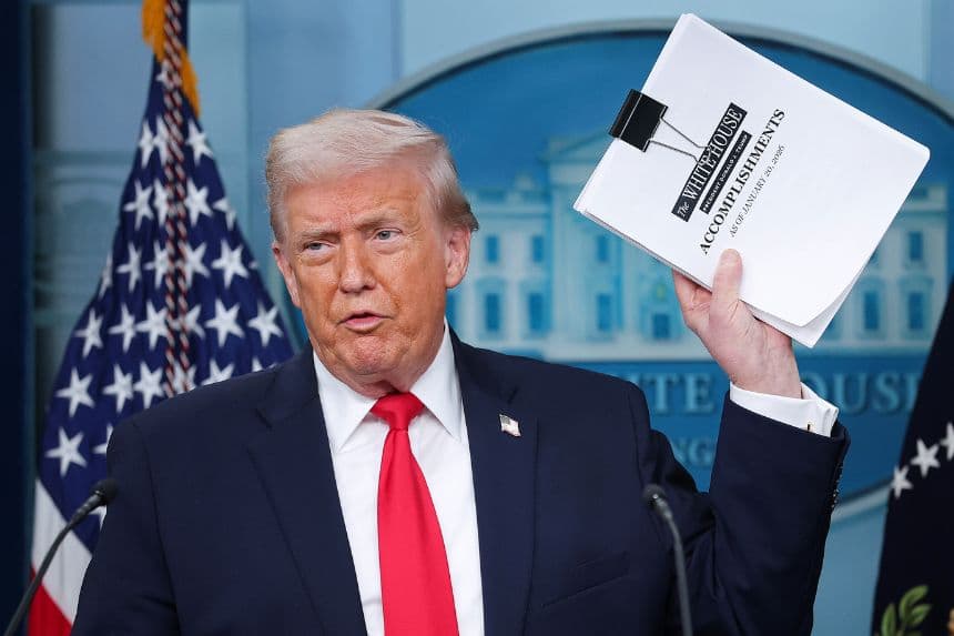 <em>El presidente de los Estados Unidos, Donald Trump, muestra una pila de papeles con la etiqueta "Logros de la Casa Blanca" al llegar a una rueda de prensa en la sala James S. Brady de la Casa Blanca el 20 de enero de 2026 en Washington, D.C. (Kevin Dietsch/Getty Images)</em>