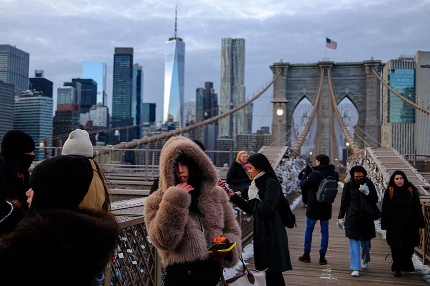 La gente desafía las bajas temperaturas mientras camina por el puente de Brooklyn, en el distrito de Manhattan de la ciudad de Nueva York, el 21 de enero de 2026. (CHARLY TRIBALLEAU / AFP a través de Getty Images)
