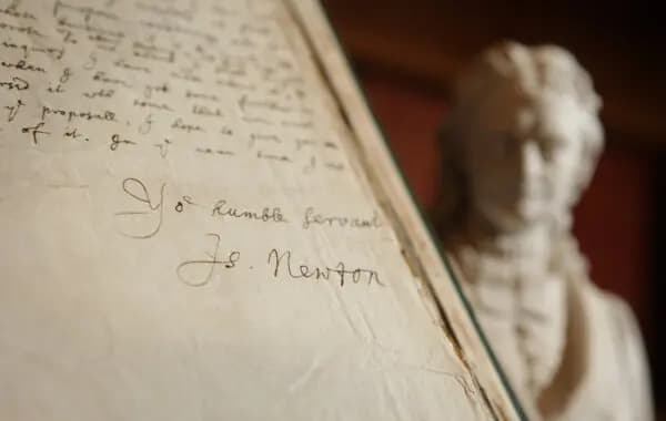 <em>La firma de Isaac Newton contenida en un libro de sus cartas se exhibe junto a una estatua suya en la Royal Society de Londres el 24 de noviembre de 2009. (Peter Macdiarmid/Getty Images)</em>
