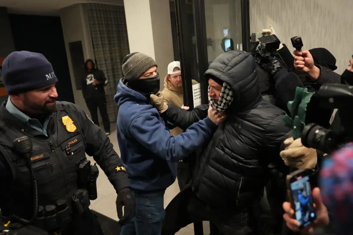 Un hombre junto a un agente de policía agarra a un manifestante durante una protesta contra las operaciones federales de control de la inmigración en Minneapolis el 25 de enero de 2026. (Adam Gray/AP Photo)